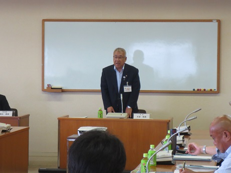 壁にホワイトボードが設置されている室内で、左右と手前に座っている参加者の前で挨拶を行っている市長の写真