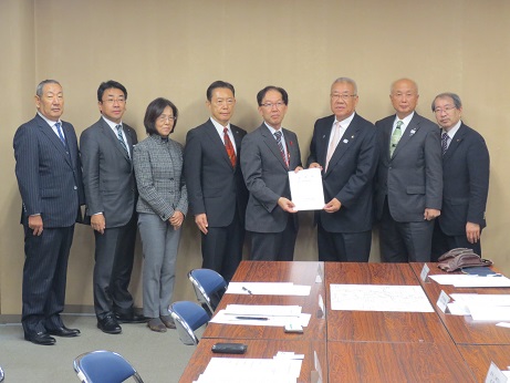 野田県土整備部長と市長が一緒に要望書を持ち、他6名の関係者が横一列に並んで立っている写真