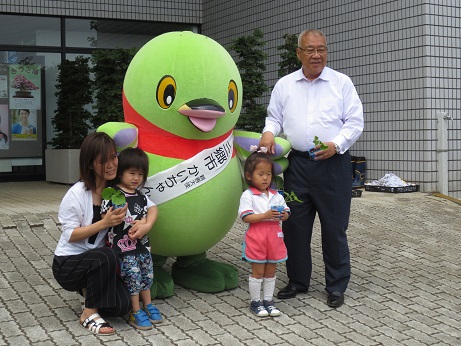マスコットキャラクターかいちゃんの前に2名の子どもと母親、右側に市長が立っている記念写真