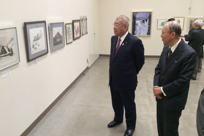 絵画作品が展示されている室内で市長の左側に立っている男性の説明を聞きながら作品を鑑賞している市長の写真