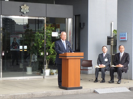 総合防災庁舎の建物入口前に設置された演壇で挨拶を行っている市長の写真