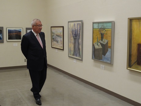 展示室内の壁に飾られた絵画作品を鑑賞している市長の写真