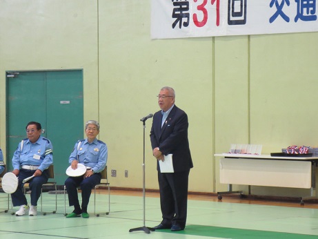 左側の椅子に座っている2名の警察官の手前に設置されたマイクスタンドの前で挨拶を行っている市長の写真