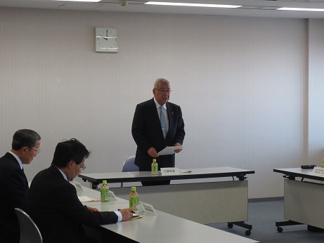 10時の位置を示した時計が飾られた室内で、席から立ち上がり挨拶を行っている市長の写真
