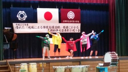 赤色や黄色、緑色にピンク色、青色のマントやお面をつけた5名のけやきレンジャーの方々がステージの上でポーズを決めている感謝の会の様子の写真