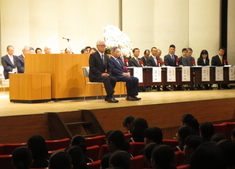 ステージの右側に設置された長机の席に関係者が座り、演壇の前に設置された2脚の椅子に福岡先生と木津先生が座っている写真