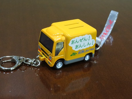 黄色のボティの側面に「あんぜん！あんしん！」と書かれたトラックの形をした光るトラック型防犯ブザーをアップで撮影した写真