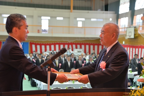 ステージ上で遠藤町長と向かい合った市長が額縁に入った感謝状を受け取っている様子をアップで撮影した写真