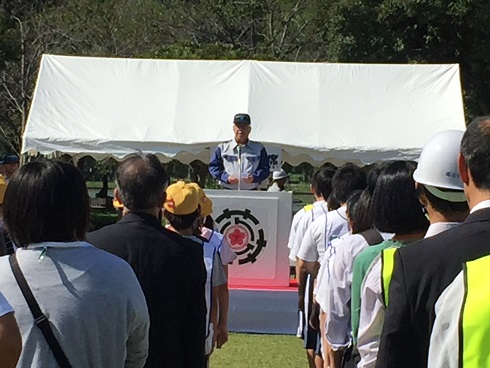 参加者とテント前の檀上の市長が向かい合って立ち訓示を行っている様子の写真