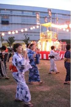 提灯が飾られ紅白幕で囲われた櫓の周りを、様々な柄の浴衣を着た市民の方々が踊っている様子の写真