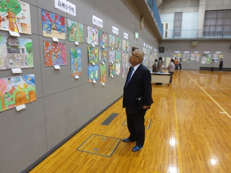 体育館の壁に学校別に展示されている絵画作品を鑑賞している市長の写真