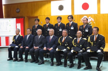 前列の椅子に市長を中央に6名の関係者が座り、後列に5名の団員が立っている記念写真