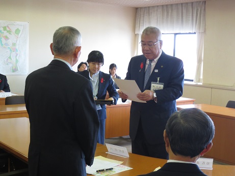 席から立ち上がった男性に向かい合った市長が委託書を交付している様子の写真