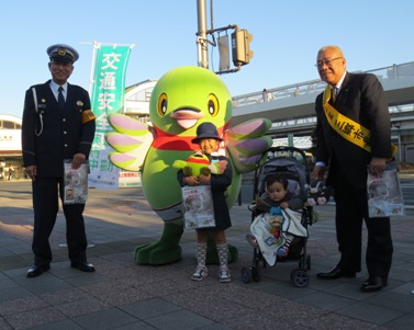 警察署長と市長の間に、マスコットキャラクターかいちゃんとベビーカーに乗った小さな子どもと、制服を着用した笑顔の女の子が立っている写真