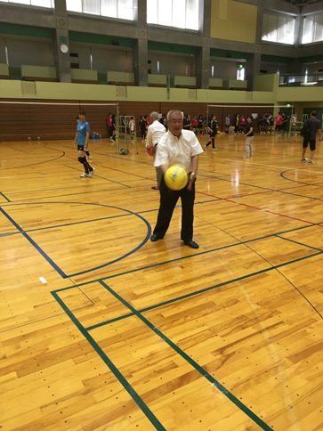 三郷市長が飛んでくる黄色いバレーボールを打ち返そうとしているところを正面から撮影した始球式の写真