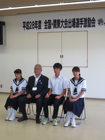「平成28年度全国・関東大会出場選手激励会」と書かれた横幕が貼られtた室内で、市長と3名の生徒が設置されたパイプ椅子に並んで座っている写真