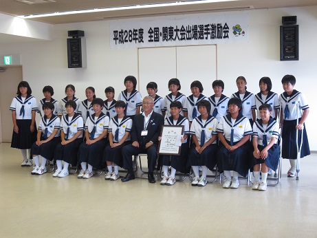 「平成28年度全国・関東大会出場選手激励会」と書かれた横幕が貼られた室内で、市長を中央に前列の椅子に8名の女子生徒、後列に13名の女子生徒が並んでいる記念写真