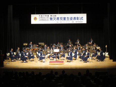 制服を着た南中学校吹奏楽部の皆さんがステージ全体に扇形に設置された椅子に座り演奏を行う前の様子の写真