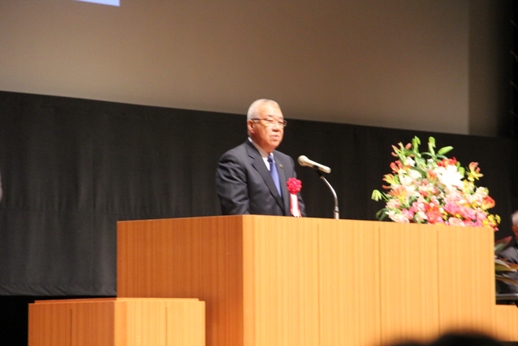 胸章リボンをつけた市長が檀上で挨拶を行っている様子をアップで撮影した写真