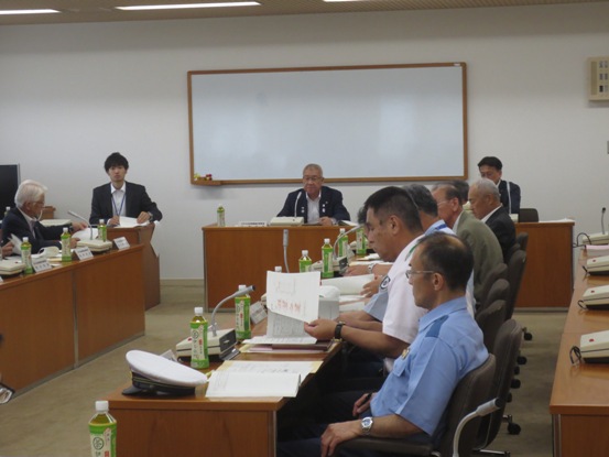 壁に備え付けられたホワイトボードの前の席に座っている市長、手前に向かい合わせで設置された席に関係者の方々が座っている会議の様子の写真