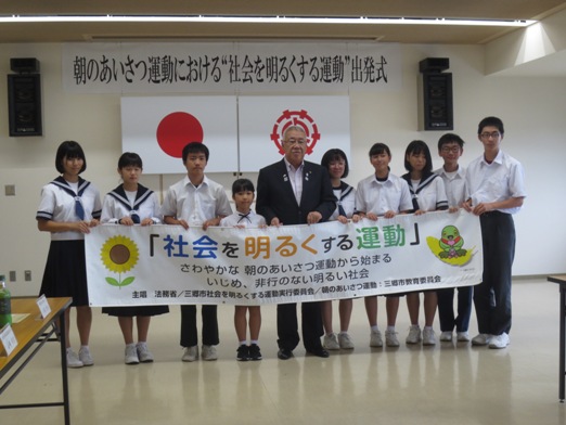 「社会を明るくする運動」と書かれた横断幕を、市長を中央に9名の子どもたちが持って並んでいる写真