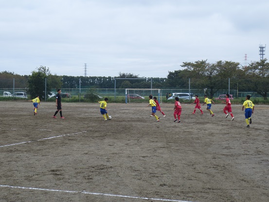黄色と赤色のユニホームを着たチームの子どもたちがサッカーを行っている様子の写真