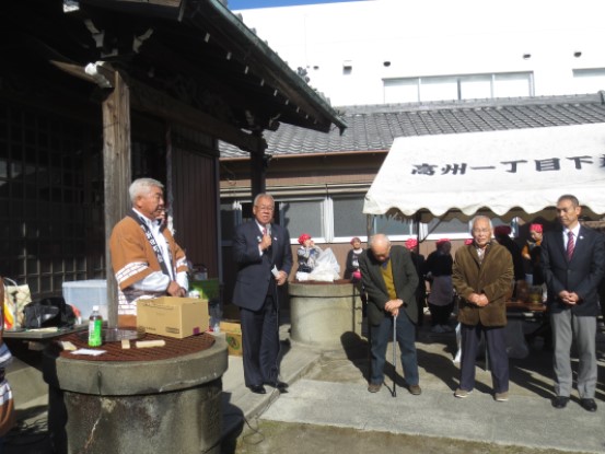 神社の拝殿前に設置されたテントの前に関係者が立ち、左手前に法被を着た男性が立ち、その隣で挨拶を行っている市長の写真
