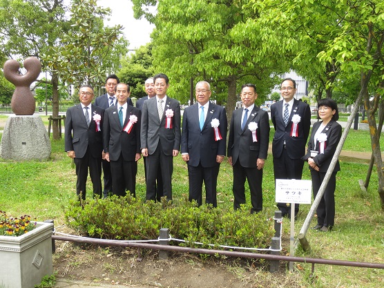 におどり公園で三郷市長とと8人の関係者の方々が横に並び、植樹したサツキと一緒に記念撮影をしている写真