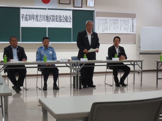 黒板に「平成30年度吉川地区防犯協会総会」の紙が貼られ、長机に座る3名の関係者の間に立っている市長が挨拶をしている写真
