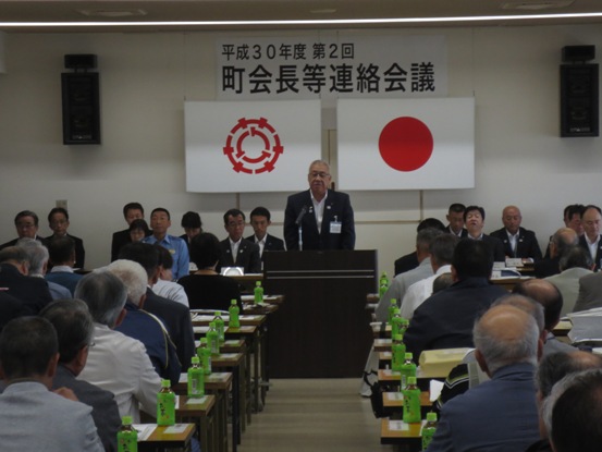 「平成30年度第2回町会長等連絡会議」のボードが吊られている会場で、椅子に着席している多くの関係者たちを前に話をしている市長の写真