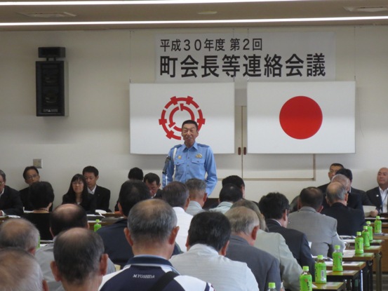 「平成30年度第2回町会長等連絡会議」のボードが吊られている会場で、椅子に着席している多くの関係者たちを前に話をしている南雲署長の写真
