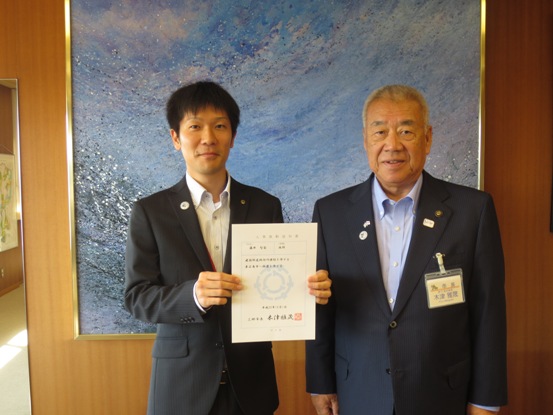 辞令を持った男性職員と市長が並んで記念撮影をしている写真