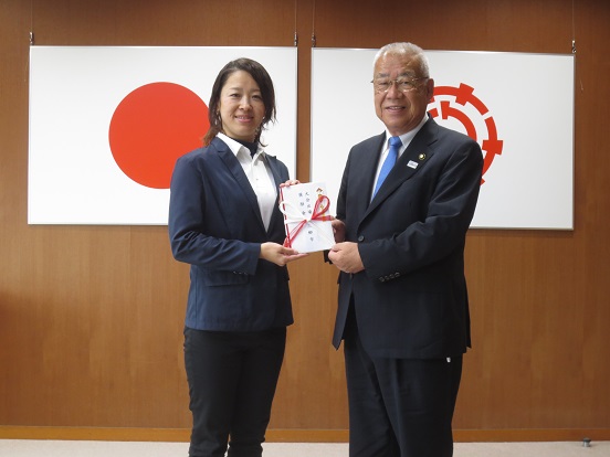 山下香織選手と木津市長が一緒に封筒を持って記念撮影をしている写真