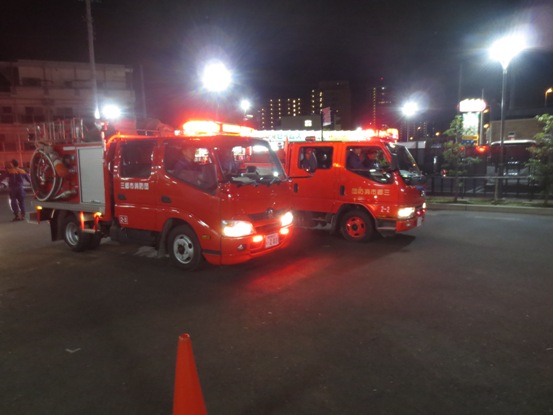 2台の消防車がライトを点けて敷地から発進している写真