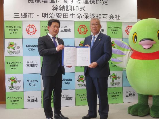 調印した協定書を手に常峰光雄越谷支社長と木津市長