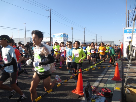 様々なデザインのランニングウェアを着用した参加者たちがスタート地点から一斉に走っている様子の写真