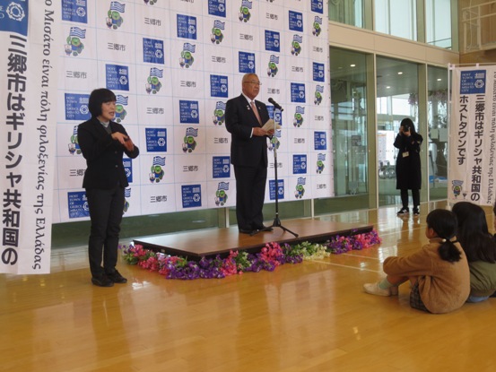 子どもたちが座っている会場で、周りに花が飾られた演台に立った市長が、挨拶をしている写真