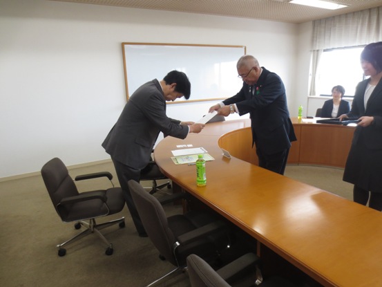 Uの字型のテーブルが設置されている部屋で、市長から関係者へ委嘱書が手渡されている写真