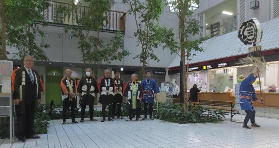 三郷鳶組合の方々が市民ホールにて木遣りを唄い、窓口前でまとい振りを行う様子を写した写真