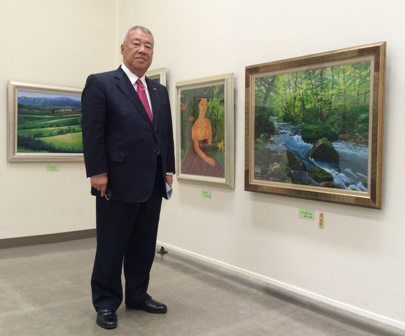 壁に額入りの絵画作品が展示され、市長賞を受賞した絵画の前に立つ市長の写真