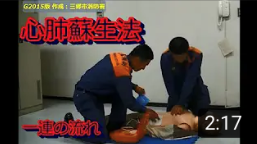 右側の隊員がマネキンに心臓マッサージを施し、左側の隊員がマネキンの心臓付近に電極パッドを貼っている心肺蘇生法を行っている様子の写真（一連の流れ～心肺蘇生法手順【Ｇ2015版 三郷市消防署作成】（YouTubeのサイトへリンク））