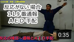 横たわっているマネキンの前で両手を大きく上げて近くの人に119番通報を依頼している隊員の写真（反応の確認・通報・ＡＥＤ手配～心肺蘇生法手順【Ｇ2015版 三郷市消防署作成】（YouTubeのサイトへリンク））
