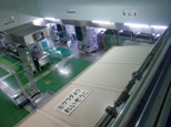 奥に緑の床が見え手前に冷蔵庫、奥に機械のある給食センターの室内を上から写した写真