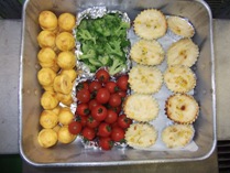 左からトレーに並べられた卵焼き、ブロッコリー、ミニトマト、ミニグラタンの写真