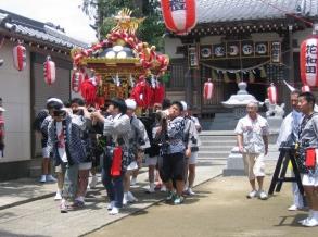 神社から法被を着た男性たちが神輿を担いで出発している様子の写真