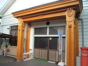 玄関ポーチに設置された4本の柱に筋彫りの装飾が施されている彦成小学校講堂記念館入り口の写真