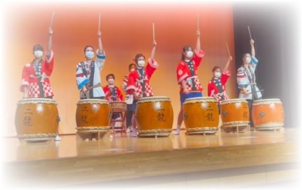 法被を着た8名のメンバーがステージ上で和太鼓を演奏している定期演奏会の写真