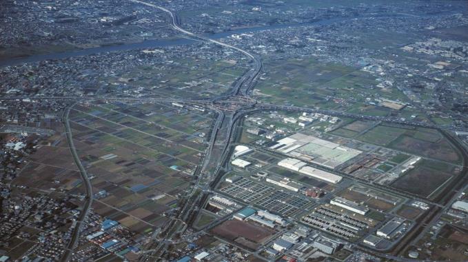 インターチェンジ付近の広々とした農地と街並みを上空から撮った写真
