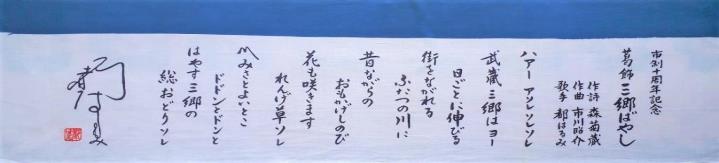 上部に青のラインが入り、筆文字で葛飾三郷ばやしの歌詞が書かれている手ぬぐいの写真