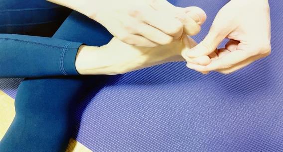 右足の親指を上方向、人差し指を下方向に引っ張り血行を良くしている様子の写真